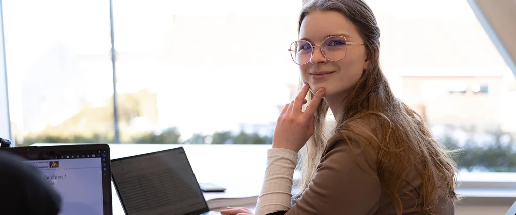 Étudiante seule souriant devant un ordinateur portable