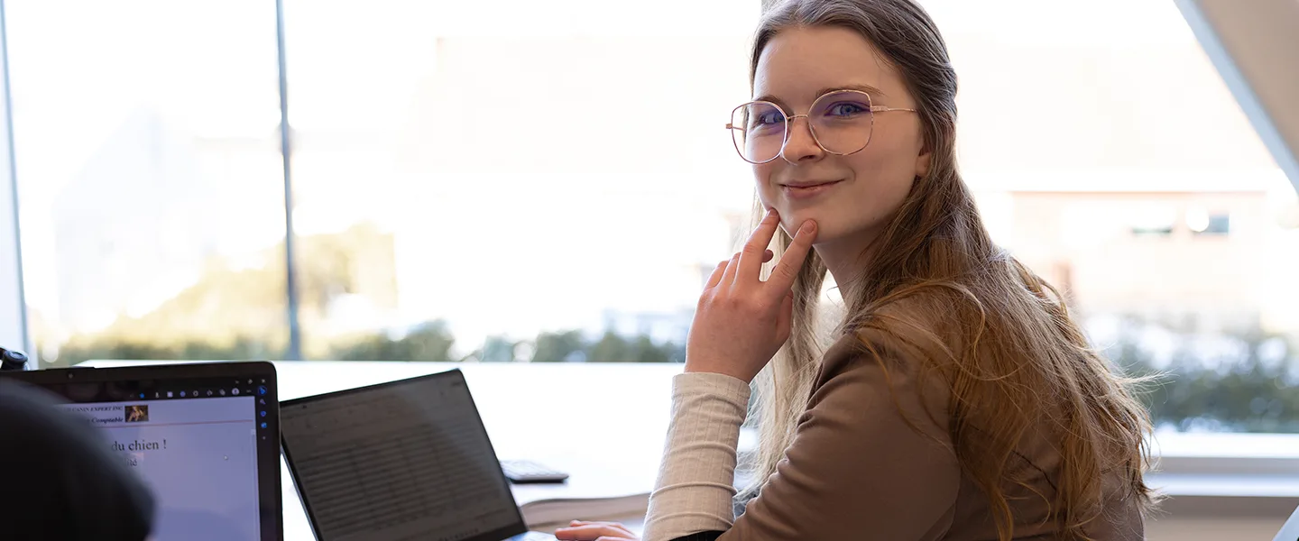 Étudiante seule souriant devant un ordinateur portable