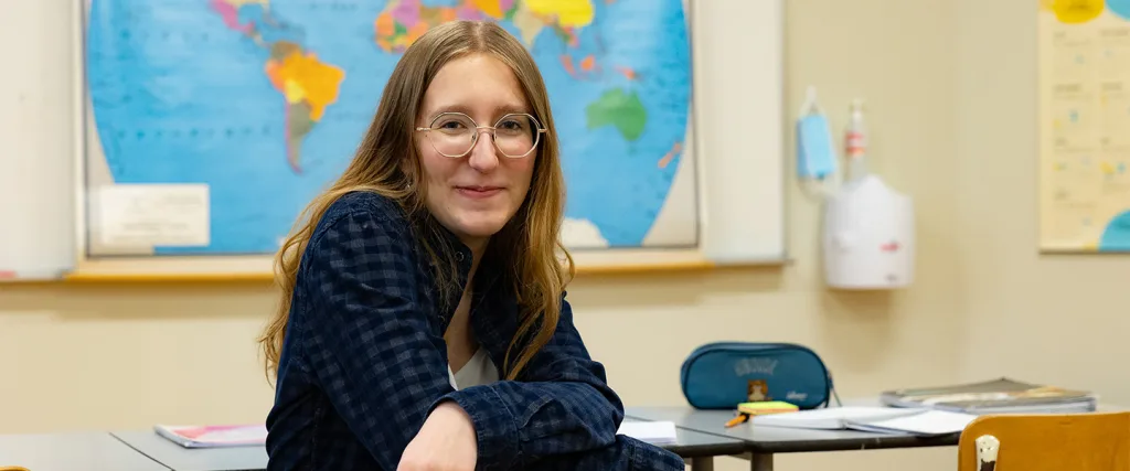 Étudiante assise à un bureau devant une carte du monde