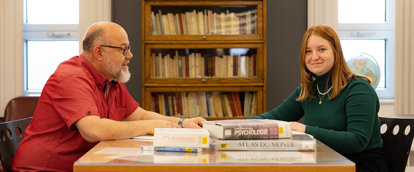Enseignant et étudiante en discussion autour d'ouvrages de référence