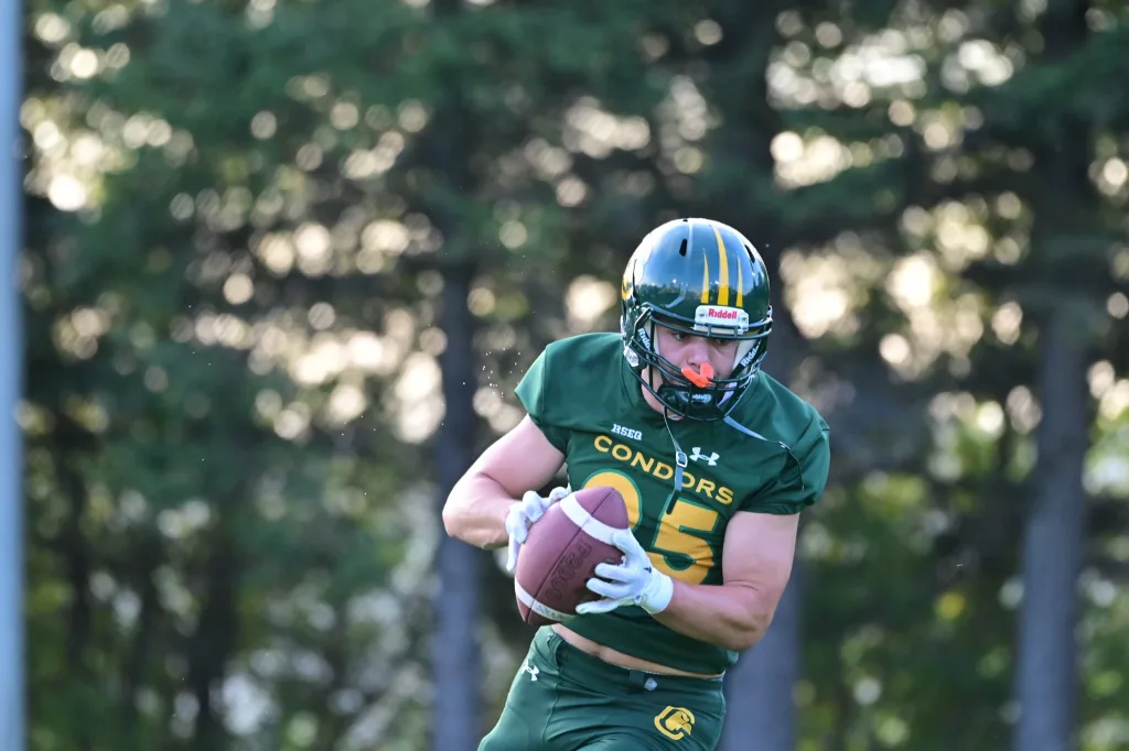 Joueur Condors football qui traverse le terrain avec le ballon
