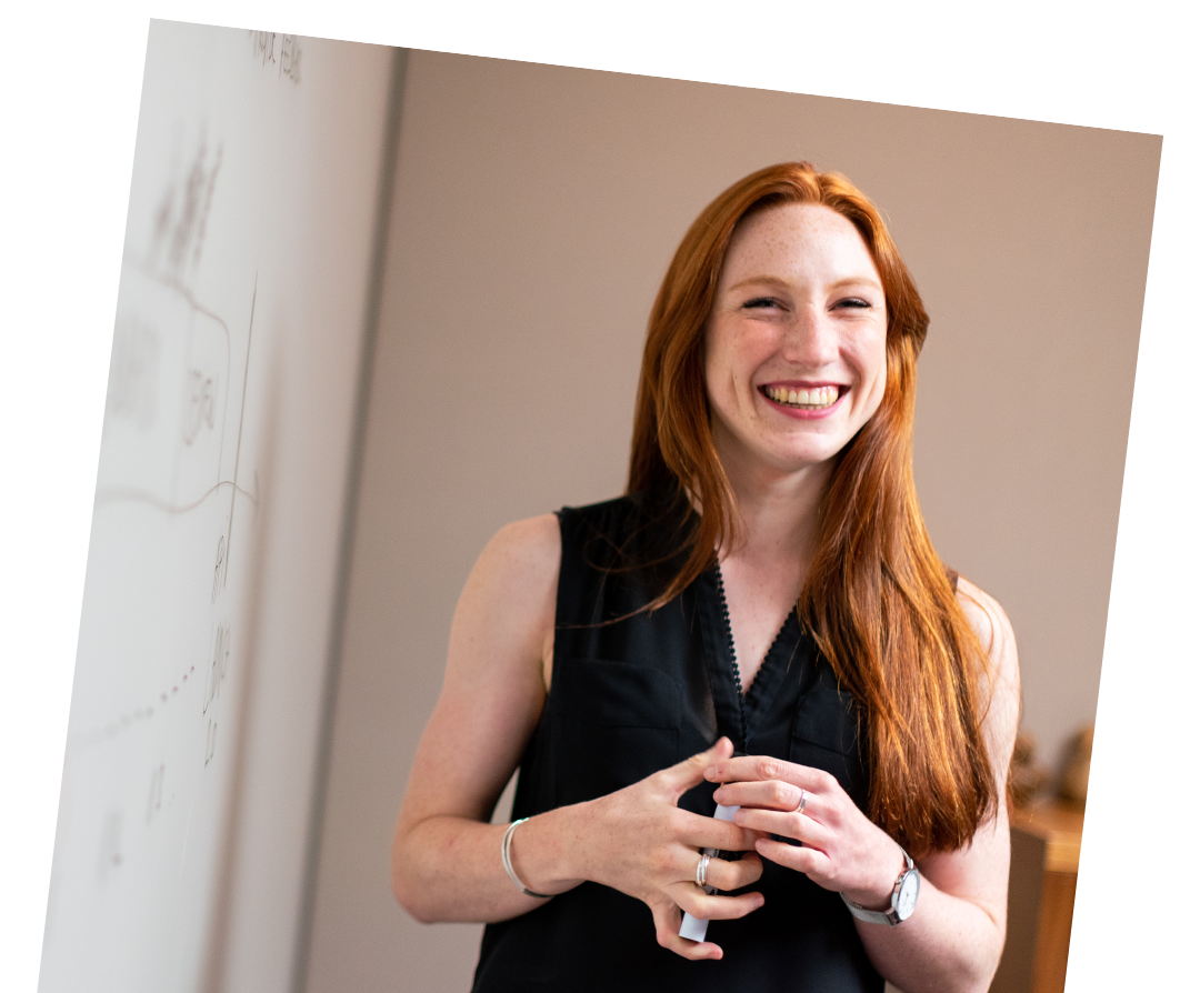 Femme souriante devant un tableau blanc